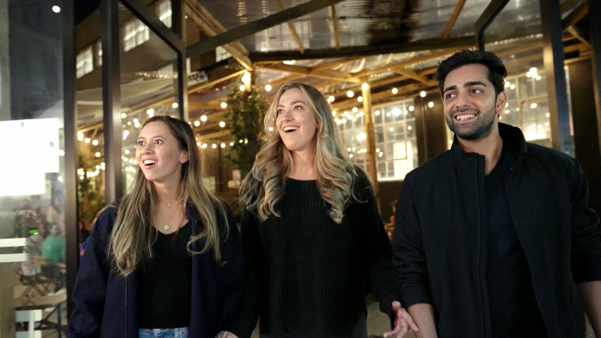 A team of colleagues in winter coats laughing over a riddle on a phone on a London street in December
